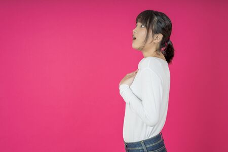 asian woman keeps hands on chest near heart, shows her kindness or favour, expresses sincere emotions, being kind hearted and honest. Body language and real feelings conceptの写真素材