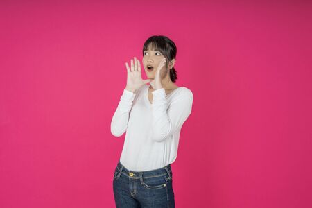 Do not miss. Young asian woman shouting. Shout. Crying emotional  woman screaming on pink studio background. Female half-length portrait. Human emotions, facial expression concept. Trendyの写真素材