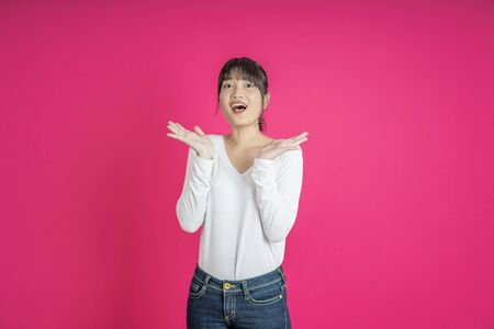 Do not miss. Young asian woman shouting. Shout. Crying emotional  woman screaming on pink studio background. Female half-length portrait. Human emotions, facial expression concept. Trendyの写真素材