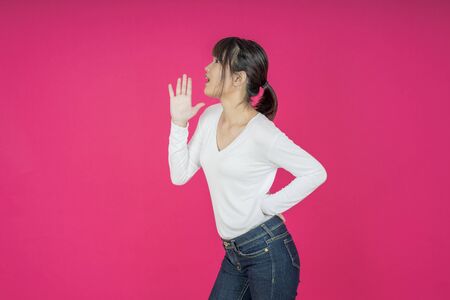 Do not miss. Young asian woman shouting. Shout. Crying emotional  woman screaming on pink studio background. Female half-length portrait. Human emotions, facial expression concept. Trendyの写真素材