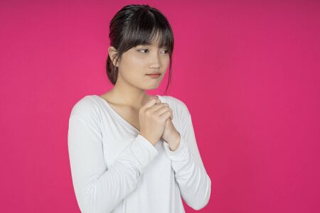 asian woman keeps hands on chest near heart, shows her kindness or favour, expresses sincere emotions, being kind hearted and honest. Body language and real feelings conceptの写真素材