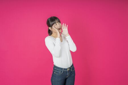 Do not miss. Young asian woman shouting. Shout. Crying emotional  woman screaming on pink studio background. Female half-length portrait. Human emotions, facial expression concept. Trendyの写真素材