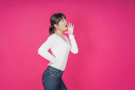 Do not miss. Young asian woman shouting. Shout. Crying emotional  woman screaming on pink studio background. Female half-length portrait. Human emotions, facial expression concept. Trendyの写真素材
