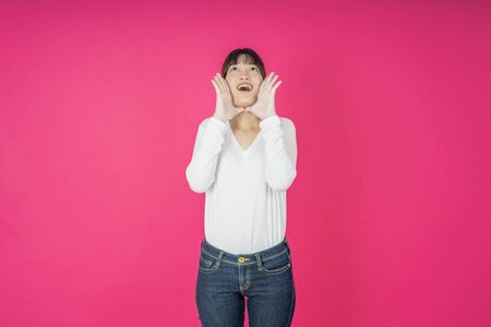 Young asian woman shouting. Shout. Crying emotional  woman screaming on pink studio background. Female half-length portrait. Human emotions, facial expression concept. Trendyの写真素材