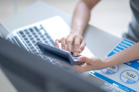 Asian business woman reviewing data in financial charts and graphs. Accounting