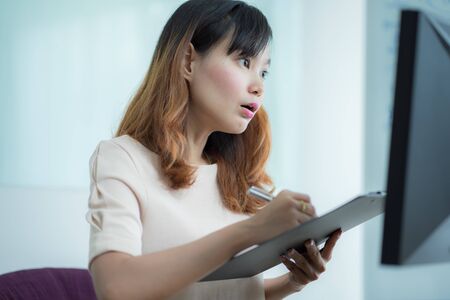Asian businesswoman laughing with joy at workplace, gladly looking at laptop screen, feeling excited about online win, watching funny video on computer, enjoying positive good news in internetの写真素材