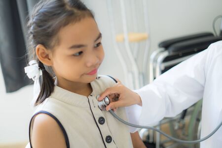 Asian doctor examining a little girl by stethoscopeの写真素材