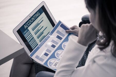 Asian business woman reviewing data in financial charts and graphs. Accountingの写真素材