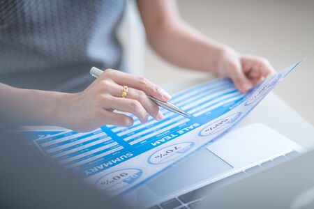 Asian business woman reviewing data in financial charts and graphs. Accountingの写真素材