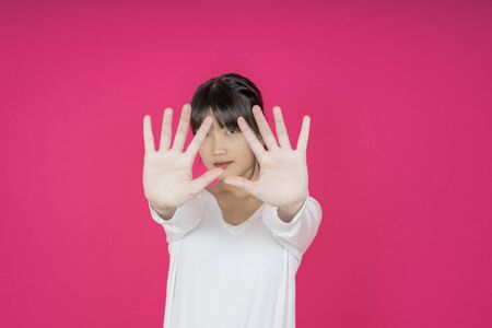 young asian woman protects herself by exposing her hand in front of herの写真素材