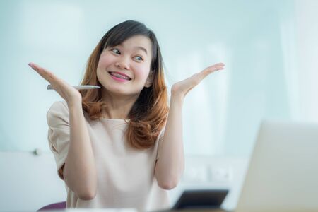Asian businesswoman laughing with joy at workplace, gladly looking at laptop screen, feeling excited about online win, watching funny video on computer, enjoying positive good news in internetの写真素材