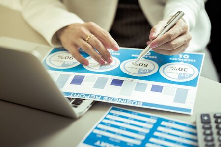 Asian business woman reviewing data in financial charts and graphs. Accountingの写真素材
