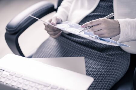 Asian business woman reviewing data in financial charts and graphs. Accountingの写真素材