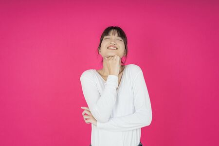 portrait of beautiful young asian woman thinking and looking upwards on pink background. The concept of perception and reflectionの写真素材