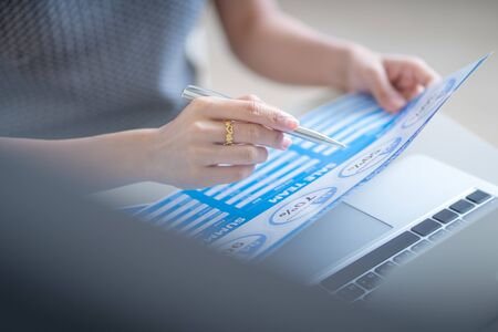 Asian business woman reviewing data in financial charts and graphs. Accountingの写真素材