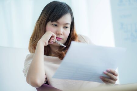Asian business woman reviewing data in financial charts and graphs. Accountingの写真素材