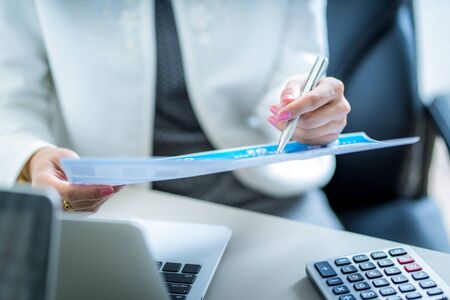 Asian business woman reviewing data in financial charts and graphs. Accounting