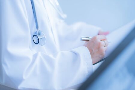 Close-up view of female doctor hands filling patient registration form. Healthcare and medical conceptの写真素材