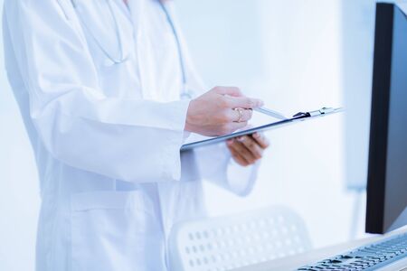 Close-up view of female doctor hands filling patient registration form. Healthcare and medical conceptの写真素材