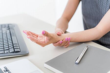 Asian woman holding her wrist pain from using computer. Office syndromeの写真素材