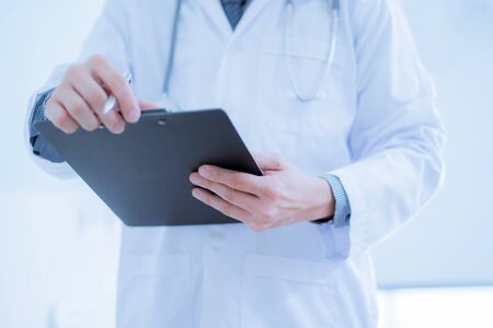Close-up Of Male Doctor Filling The Medical Formの写真素材
