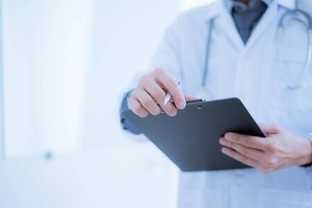 Close-up Of Male Doctor Filling The Medical Formの写真素材