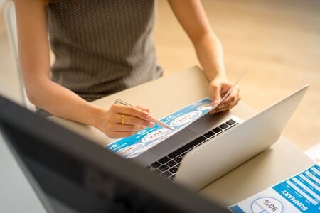 Asian business woman reviewing data in financial charts and graphs. Accountingの写真素材