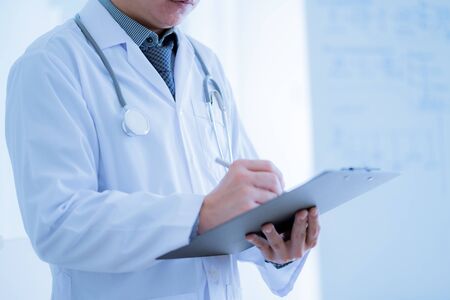 Close-up Of Male Doctor Filling The Medical Formの写真素材