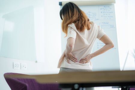 Asian woman with back pain in officeの写真素材