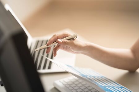 Asian business woman reviewing data in financial charts and graphs. Accountingの写真素材