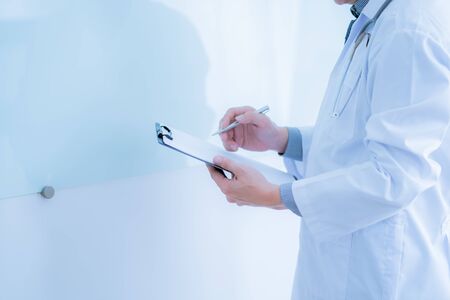 Close-up Of Male Doctor Filling The Medical Formの写真素材