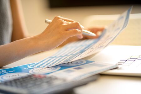 Asian business woman reviewing data in financial charts and graphs. Accountingの写真素材