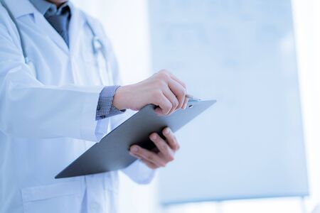 Close-up Of Male Doctor Filling The Medical Formの写真素材