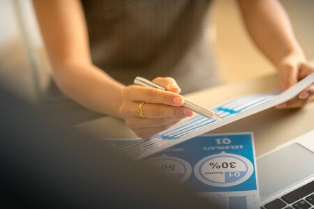 Asian business woman reviewing data in financial charts and graphs. Accounting
