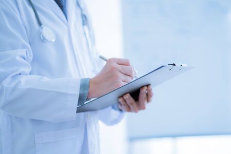 Close-up Of Male Doctor Filling The Medical Formの写真素材