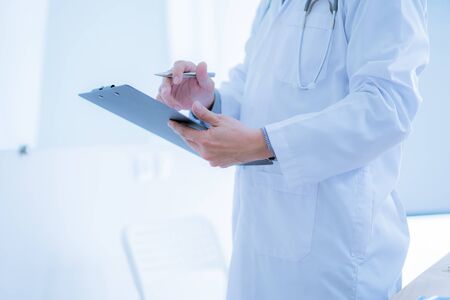Close-up Of Male Doctor Filling The Medical Formの写真素材