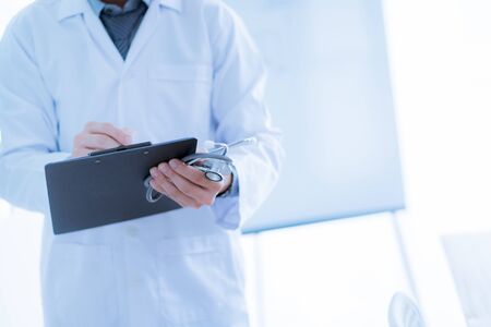 Close-up Of Male Doctor Filling The Medical Formの写真素材