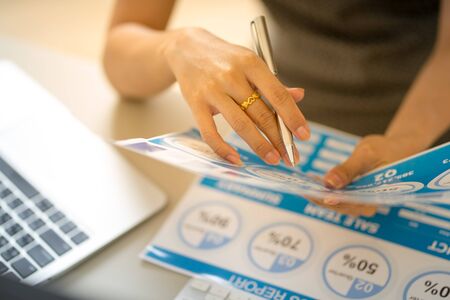 Asian business woman reviewing data in financial charts and graphs. Accounting