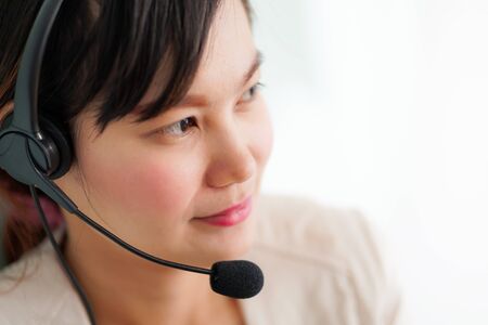 Portrait of happy smiling female customer support phone operator at workplace. Asian