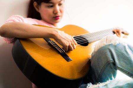 A beautiful asian woman playing acoustic guitarの写真素材
