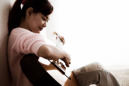 A beautiful asian woman playing acoustic guitarの写真素材