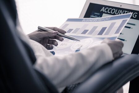 Asian business woman reviewing data in financial charts and graphs. Accountingの写真素材