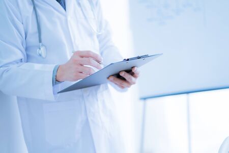 Close-up Of Male Doctor Filling The Medical Formの写真素材