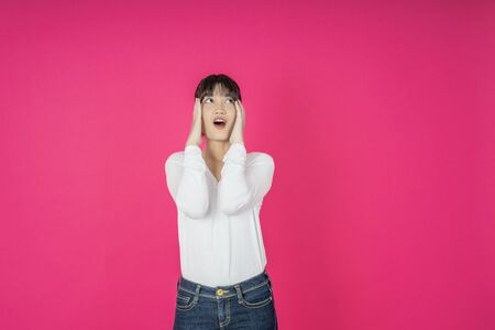 Do not miss. Young asian woman shouting. Shout. Crying emotional  woman screaming on pink studio background. Female half-length portrait. Human emotions, facial expression concept. Trendyの写真素材