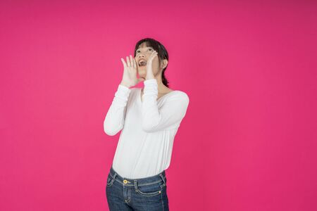 Do not miss. Young asian woman shouting. Shout. Crying emotional  woman screaming on pink studio background. Female half-length portrait. Human emotions, facial expression concept. Trendyの写真素材
