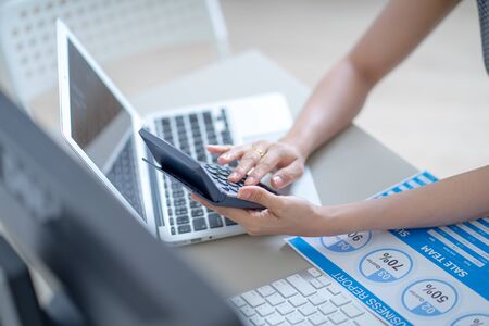 Asian business woman reviewing data in financial charts and graphs. Accountingの写真素材
