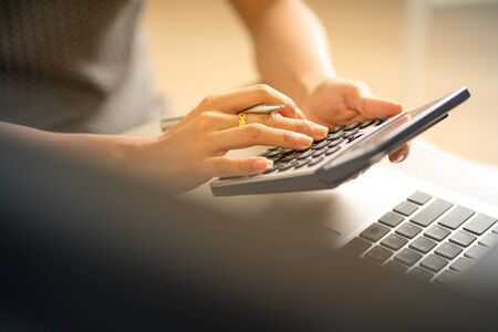 Asian business woman reviewing data in financial charts and graphs. Accounting