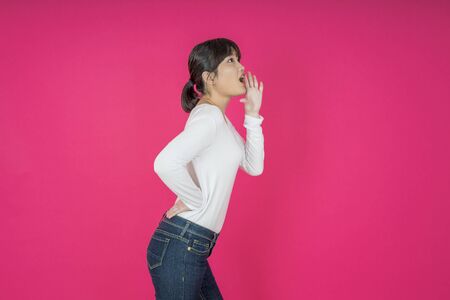 Do not miss. Young asian woman shouting. Shout. Crying emotional  woman screaming on pink studio background. Female half-length portrait. Human emotions, facial expression concept. Trendyの写真素材