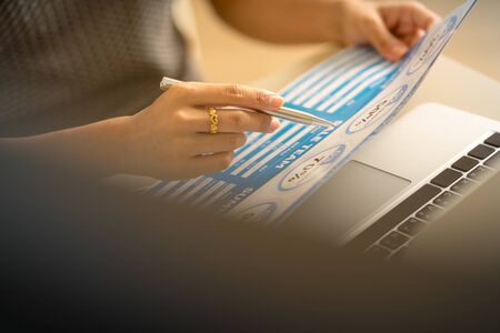 Asian business woman reviewing data in financial charts and graphs. Accountingの写真素材