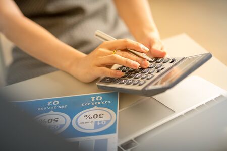 Asian business woman reviewing data in financial charts and graphs. Accountingの写真素材